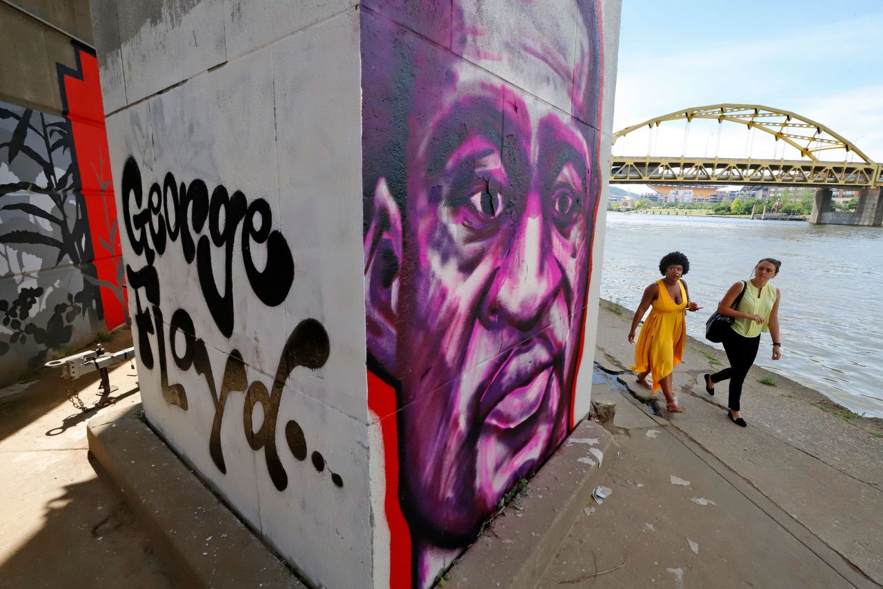 Two women pass a Floyd portrait as they walk on the Three Rivers Heritage Trail in Pittsburgh.