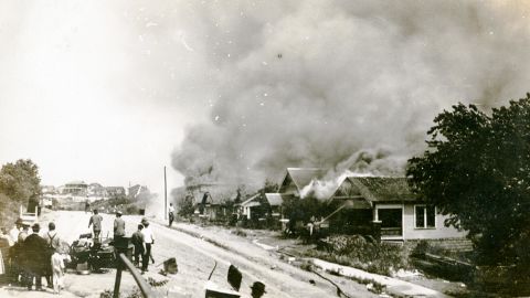 A group of people looking at smoke in the distance coming from damaged properties following the Tulsa Race Massacre, Tulsa, Oklahoma, June 1921.