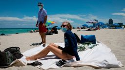 Diane, a nurse from Houston, Texas, sunbathes at the beach next to her husband, both wearing facemasks, in Miami Beach, Florida on June 16, 2020. - Florida is reporting record daily totals of new coronavirus cases, but you'd never know it looking at the Sunshine State's increasingly busy beaches and hotels. (Photo by Eva Marie UZCATEGUI / AFP) (Photo by EVA MARIE UZCATEGUI/AFP via Getty Images)