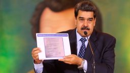 In this photo released by the Venezuela's Miraflores presidential press office, President Nicolas Maduro accuses opposition leader Juan Guaido of being behind a military raid designed to oust him, as he holds a copy of a written agreement that allegedly bears Guaido's signature as evidence, during an online press conference in Caracas, Venezuela, Wednesday, May 6, 2020. (Miraflores Palace presidential press office via AP)