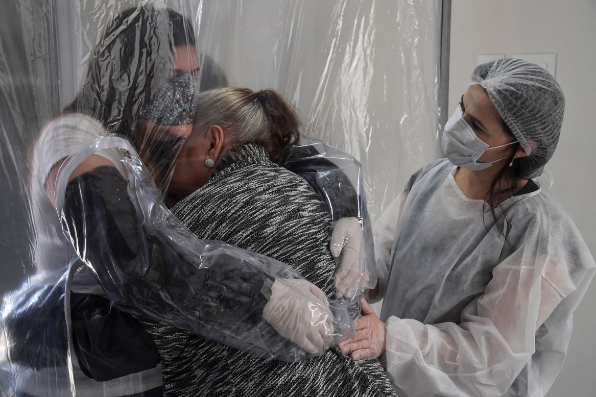 Suzane Valverde, left, hugs her mother, Carmelita, through a plastic curtain at a Sao Paulo, Brazil, nursing home on Saturday, June 13. <a href="https://www.cnn.com/2020/05/22/americas/gallery/brazil-coronavirus/index.html" target="_blank">The coronavirus is surging in Brazil,</a> which is Latin America's hardest-hit country.
