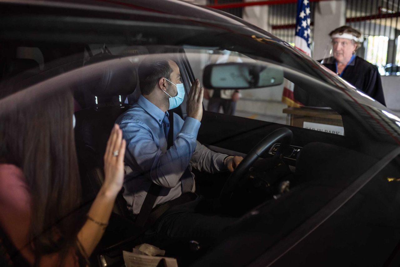 Charbel Abdo Habib and his wife, Rana El-hachem, raise their hands as Federal Magistrate Judge Patricia Morris swears them in during <a href="https://www.usatoday.com/story/news/nation/2020/06/18/immigrants-becoming-citizens-via-drive-thru-ceremonies/3213245001/" target="_blank" target="_blank">a drive-thru naturalization ceremony</a> in Detroit on June 17.