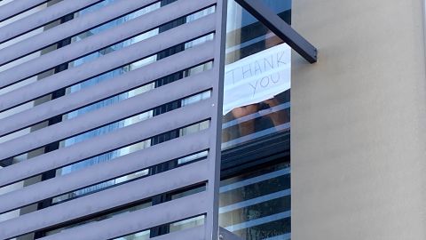 A detainee holds a sign  to the window of his Kangaroo Point hotel room: "Thank you."