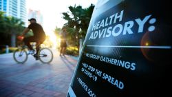 MIAMI BEACH, FL - MARCH 18: A cyclist passes a "Health Advisory" sign on March 18, 2020 in Miami Beach, Florida. Miami Beach city officials closed the area of the beach that is popular with college spring breakers and asked them to refrain from large gatherings where COVID-19 could spread.  (Photo by Cliff Hawkins/Getty Images)