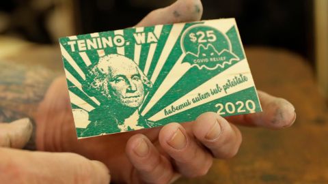 Loren Ackerman holds a piece of wooden money he printed on an 1890s-era press in Tenino, Washington.