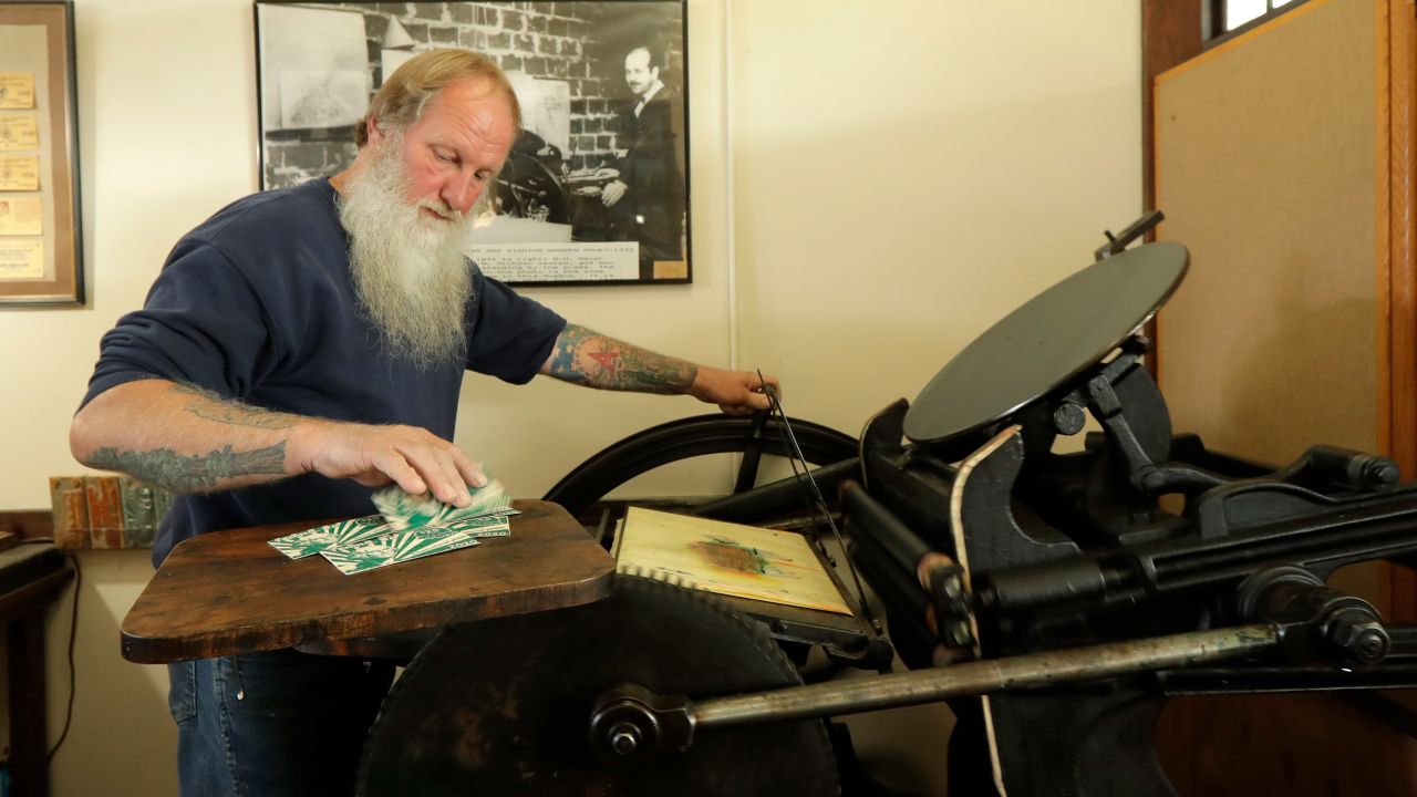 Loren Ackerman prints wooden money on an 1890s-era press in Tenino, Washington