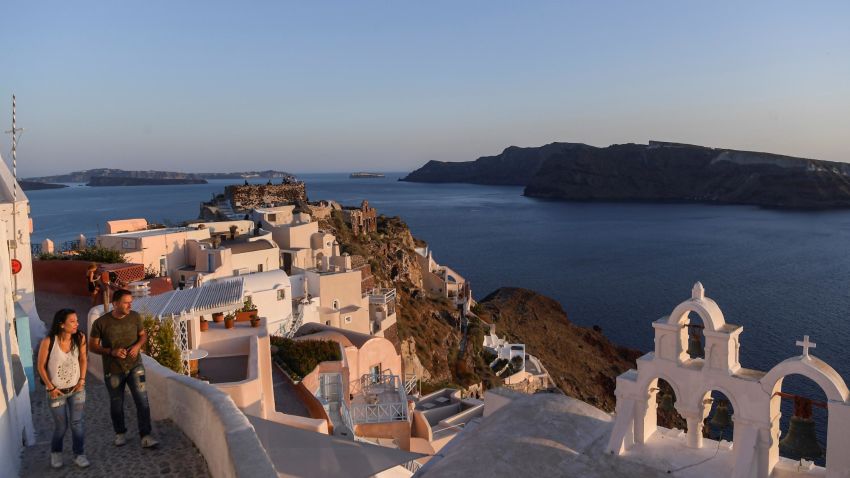 People walk in the empty alleys in the town of Oia in the island of Santorini on June 14, 2020 as the country prepares for the return of tourists to Greece from around 30 countries by air, sea and land. - From the emblematic island of Santorini, Greek Prime Minister said on June 13 that Greece is "ready to welcome tourists" in complete safety after the coronavirus lockdown, whose impact on tourism will be "significant". With its postcard landscape splashed with sunshine, the island of Santorini, one of the most touristic in Greece, awaits the return of tourists on June 15, divided between impatience to revive its effervescence and fear of seeing the coronavirus emerge from which it had so far been preserved. (Photo by ARIS MESSINIS / AFP) (Photo by ARIS MESSINIS/AFP via Getty Images)