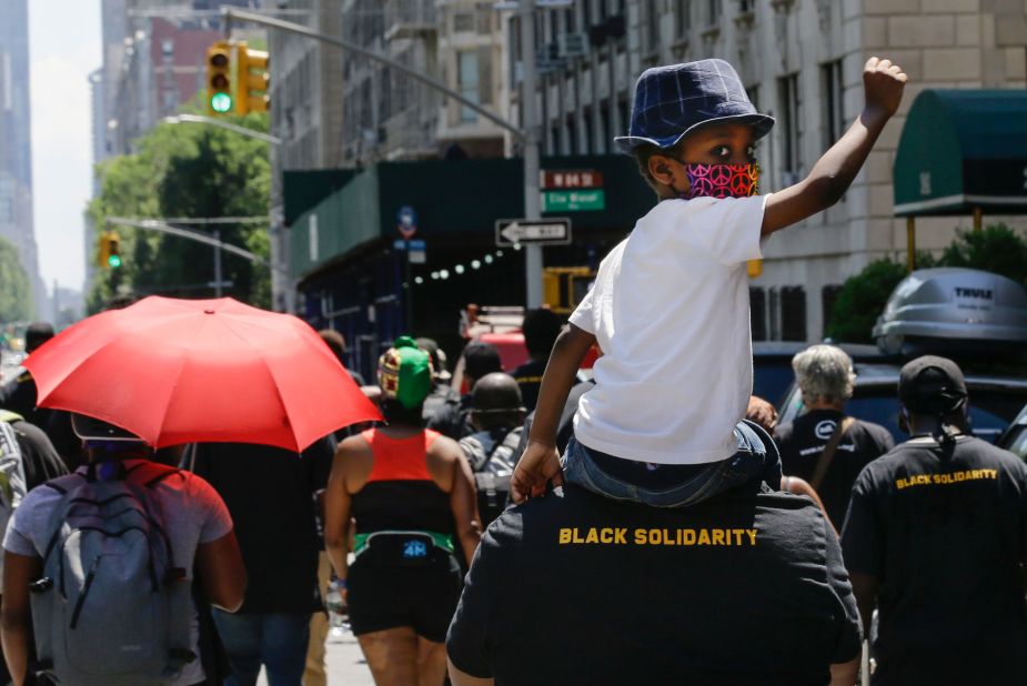 A man marches with a child on his shoulders during a Juneteenth celebration in New York.