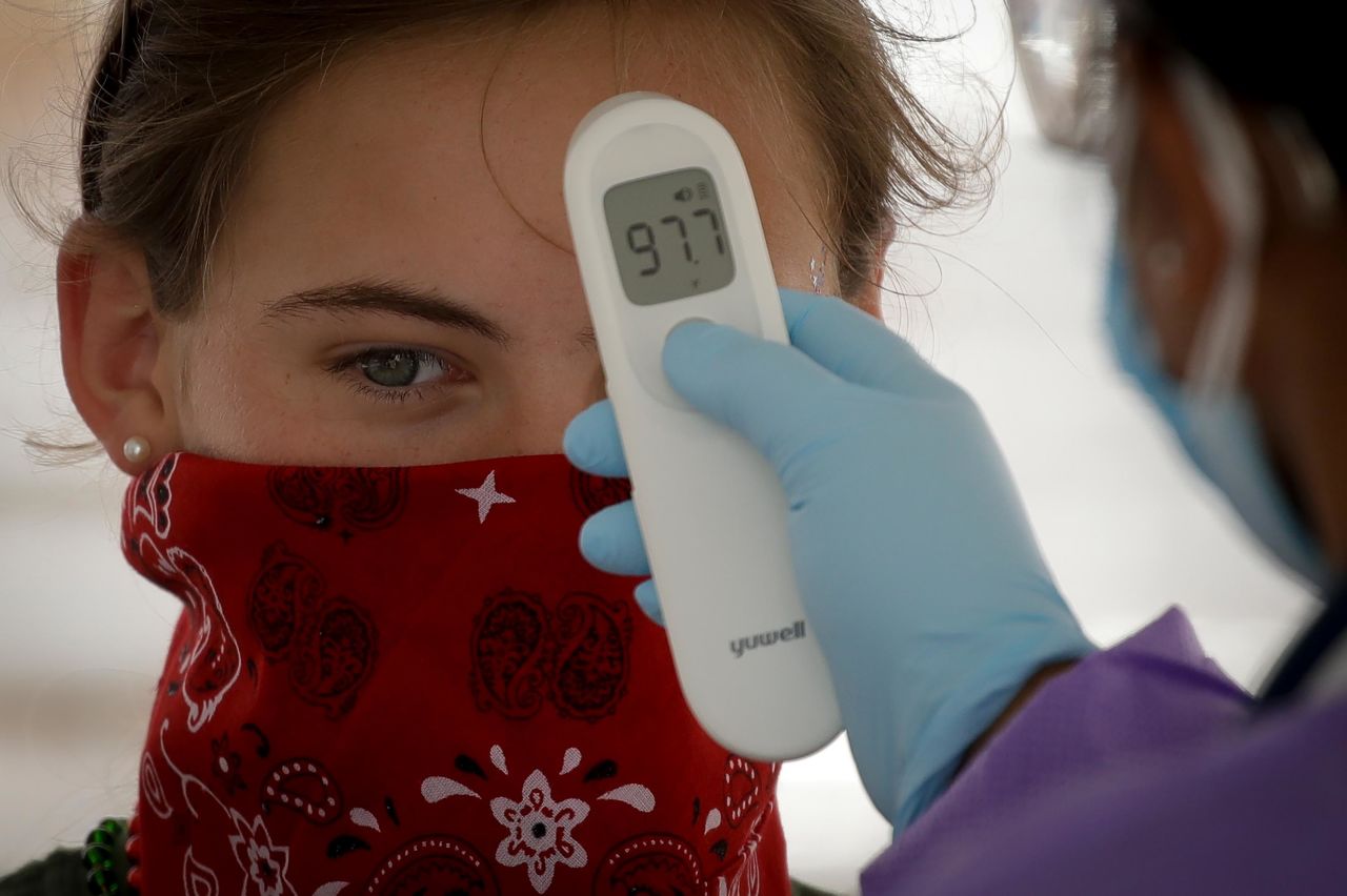 A woman has her temperature checked before entering the BOK Center.