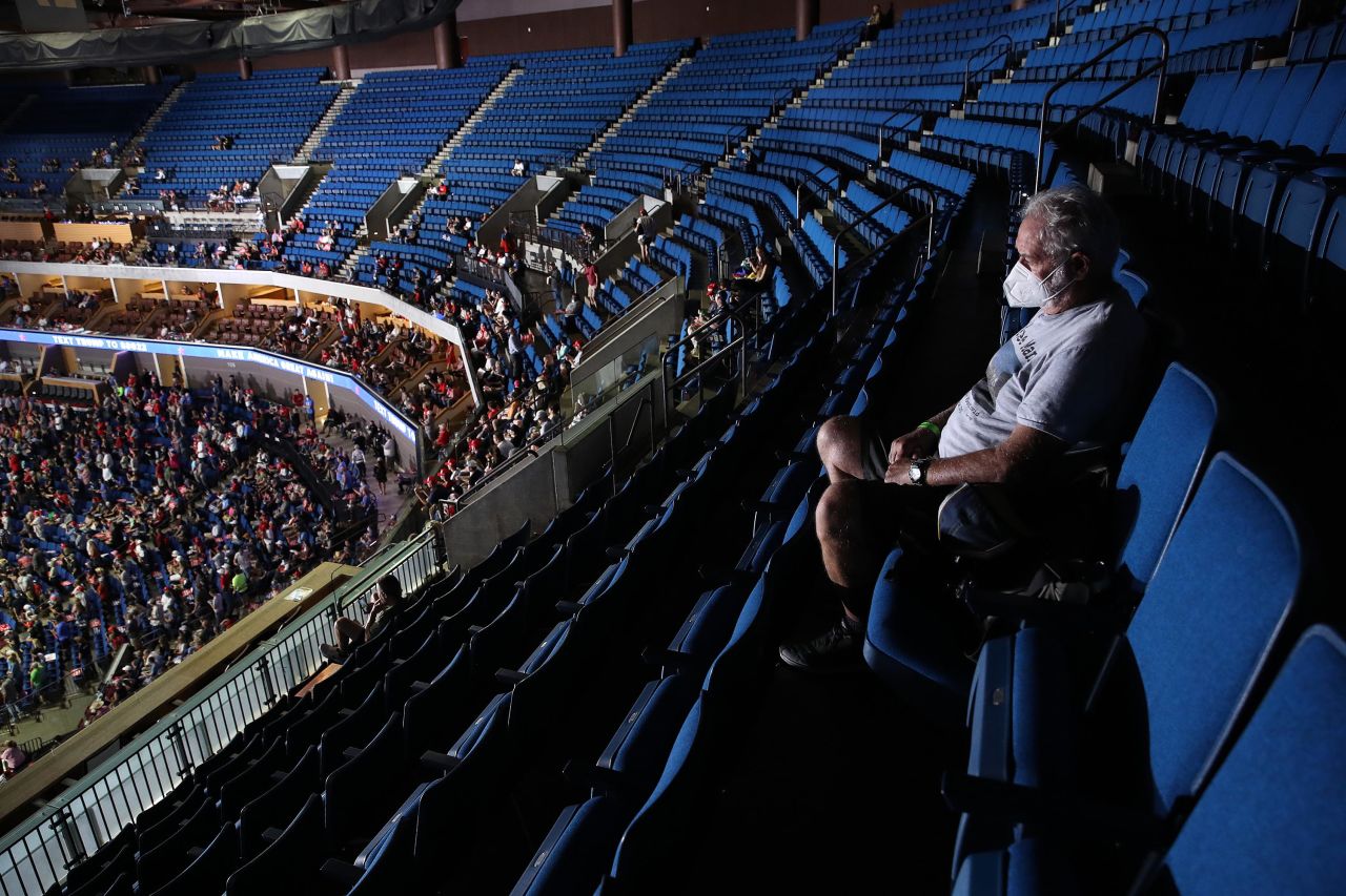 A man sits in the upper deck as people arrive for the rally.