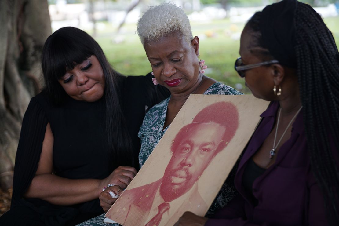 LoLisa Miller-Bradford, Roz Miller-Lloyd and Vallorie Miller hold a photo of their father Arthur Miller at the cemetery where he is buried.