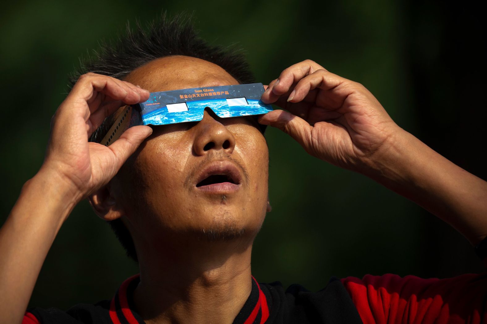 A man uses solar glasses to look at the partial eclipse near the Forbidden City in Beijing.