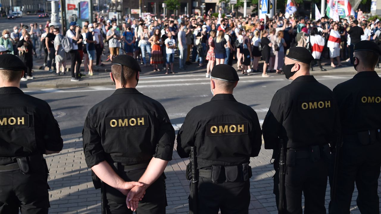 Belarus' riot police officers watch opposition supporters during a gathering to support candidates seeking to challenge President Alexander Lukashenko in August's polls in Minsk on June 19, 2020.