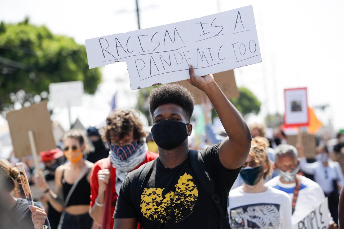 A protester carries a sign during a march in honor of Andres Guardado on Sunday, June 21, in Compton, California. Guardado was shot Thursday after Los Angeles County sheriff's deputies said they saw him with a gun.