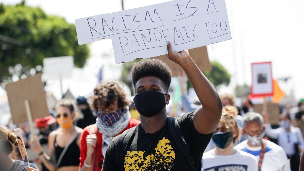 A protester carries a sign during a march in honor of Andres Guardado on Sunday, June 21, in Compton, California. Guardado was shot Thursday after Los Angeles County sheriff's deputies said they saw him with a gun.