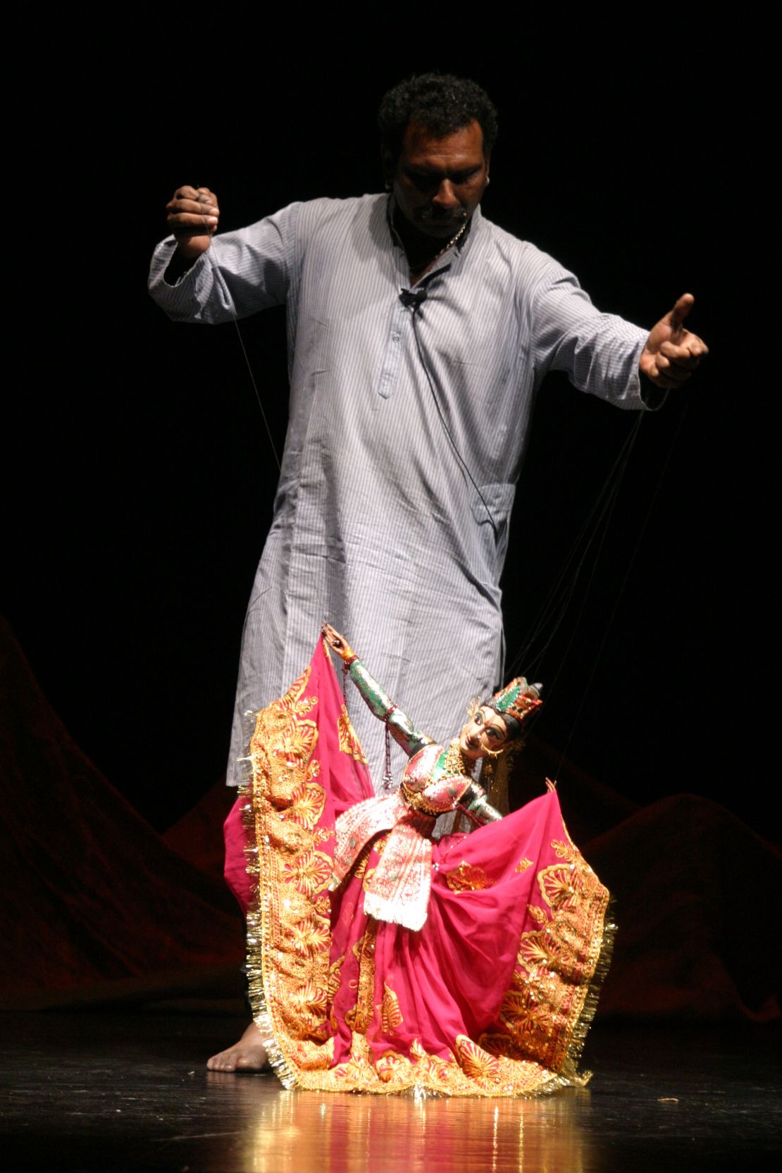 A portrait of Puran Bhatt performing with a puppet.
