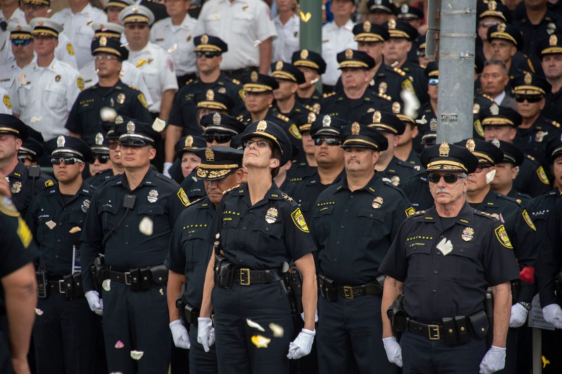 Honolulu Police Chief Susan Ballard, middle, looks up as Honolulu Fire Department and HPD helicopters drop flowers onto a procession for police Officer Tiffany-Victoria Enriquez on January 30, 2020.