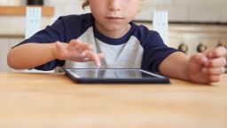 A young boy plays on a tablet.