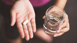 Close Up Of Girl holding Pill and glass of water.With Paracetamol.Nutritional Supplements.Sport,Diet Concept.Capsules Vitamin And Dietary Supplements.