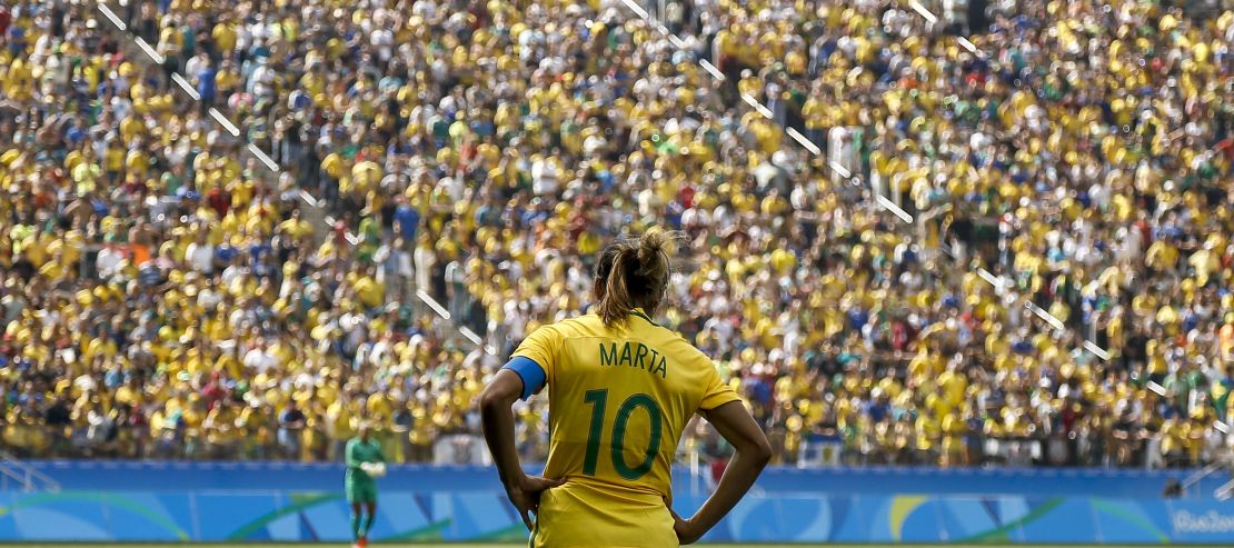 Brazil's player Marta stands facing the Brazilian crowd.