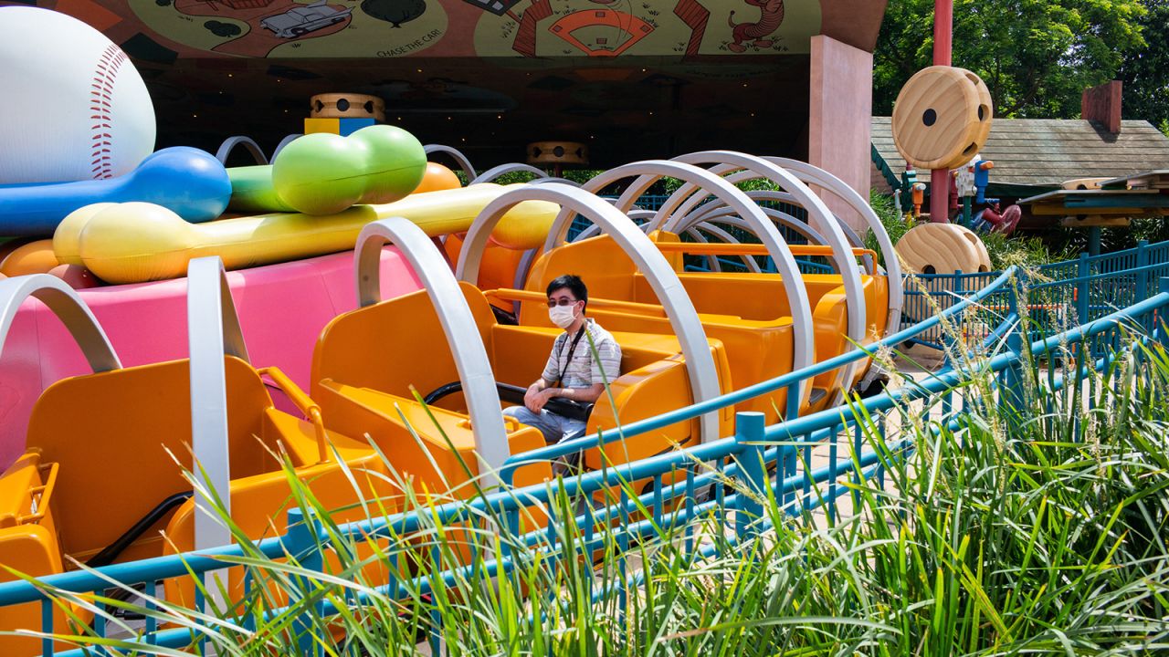 A visitor wears the now-ubiquitous face mask sits on a ride at Disneyland Resort in Hong Kong on June 18, 2020.