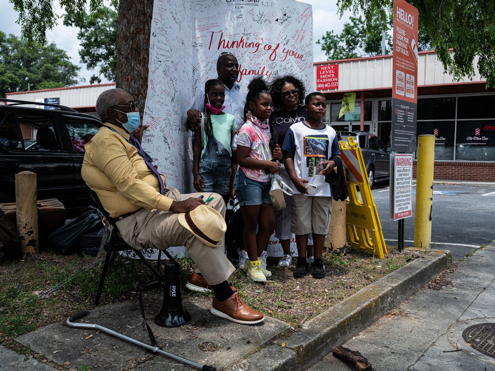 A family poses in front of a giant card that was created by the youth of Operation Correct Start's Street Academy.