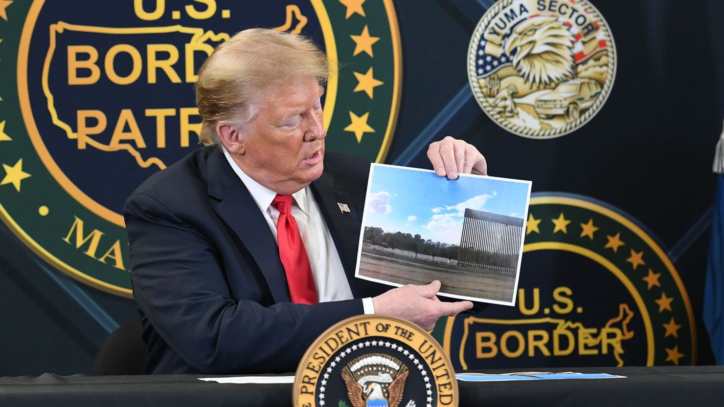 President Donald Trump shows a photo of the border wall upon arrival at the US Border Patrol station in Yuma, Arizona, June 23, 2020.