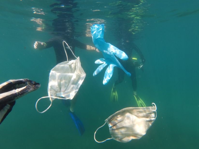 Masks and gloves float in the ocean.