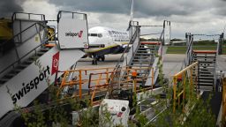An aircraft grounded due to the COVID-19 pandemic, operated by Ryanair, is pictured beyond unused Swissport stairs, on the apron at Manchester Airport in Manchester, north west England on May 1, 2020. - Irish low-cost carrier Ryanair said on Friday it planned to axe 3,000 pilot and cabin crew jobs, or 15 percent of staff, with air transport paralysed by coronavirus. Dublin-based Ryanair added in a statement that most of its flights would remain grounded until at least July and predicted it would take until summer 2022 at the earliest before passenger demand recovers. (Photo by Oli SCARFF / AFP) (Photo by OLI SCARFF/AFP via Getty Images)
