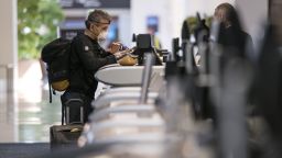 A traveler wearing a protective mask and gloves checks in at the Delta Air Lines Inc., counter at San Francisco International Airport in San Francisco, California, U.S., on Thursday, April 2, 2020. U.S. airlines have slashed flying capacity, parked planes, frozen hiring and taken other steps to cut spending as the viruss spread has reduced travel by more than 90%. Photographer: David Paul Morris/Bloomberg via Getty Images