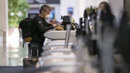 A traveler wearing a protective mask and gloves checks in at the Delta Air Lines Inc., counter at San Francisco International Airport in San Francisco, California, U.S., on Thursday, April 2, 2020. U.S. airlines have slashed flying?capacity, parked planes, frozen hiring and taken other steps to cut spending as the viruss spread has reduced travel by more than 90%. Photographer: David Paul Morris/Bloomberg via Getty Images