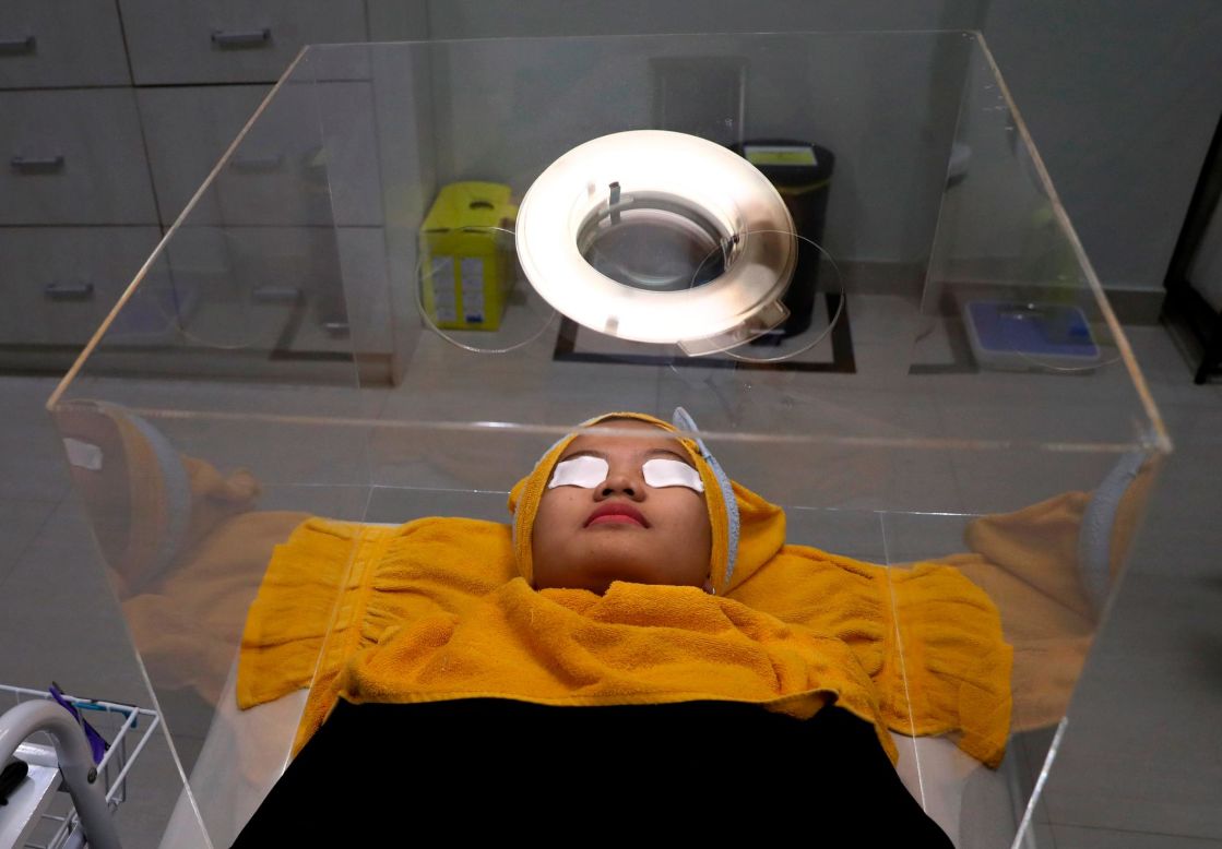 A woman lies inside a protective acrylic box as she awaits treatment at a beauty clinic in Jakarta, Indonesia, on Tuesday, June 23.