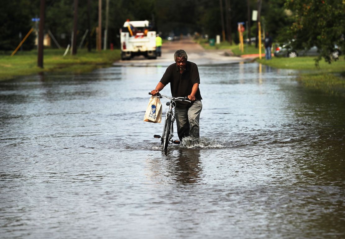 A man pushes a bike through floodwaters dumped by Hurricane Harvey in Orange, Texas, in 2017. A survey conducted after the hurricane found Black and low-income residents in Houston faced the most difficulty rebounding from the devastation.