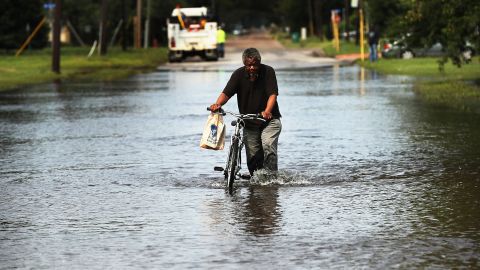 A man pushes a bike through floodwaters dumped by Hurricane Harvey in Orange, Texas, in 2017. A survey conducted after the hurricane found Black and low-income residents in Houston faced the most difficulty rebounding from the devastation.