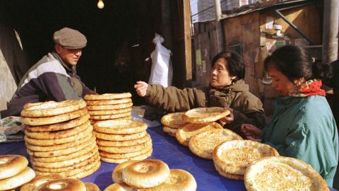 A Uyghur man sells traditional flat bread to women shoppers along Beijing's Xinjiang Street in 1999.