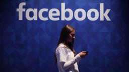 4/8/2020 - File photo dated 03/11/15 of a woman using her phone under a Facebook logo, as it has launched a new app for couples to privately message each other. (Photo by PA Images/Sipa USA) *** US Rights Only ***