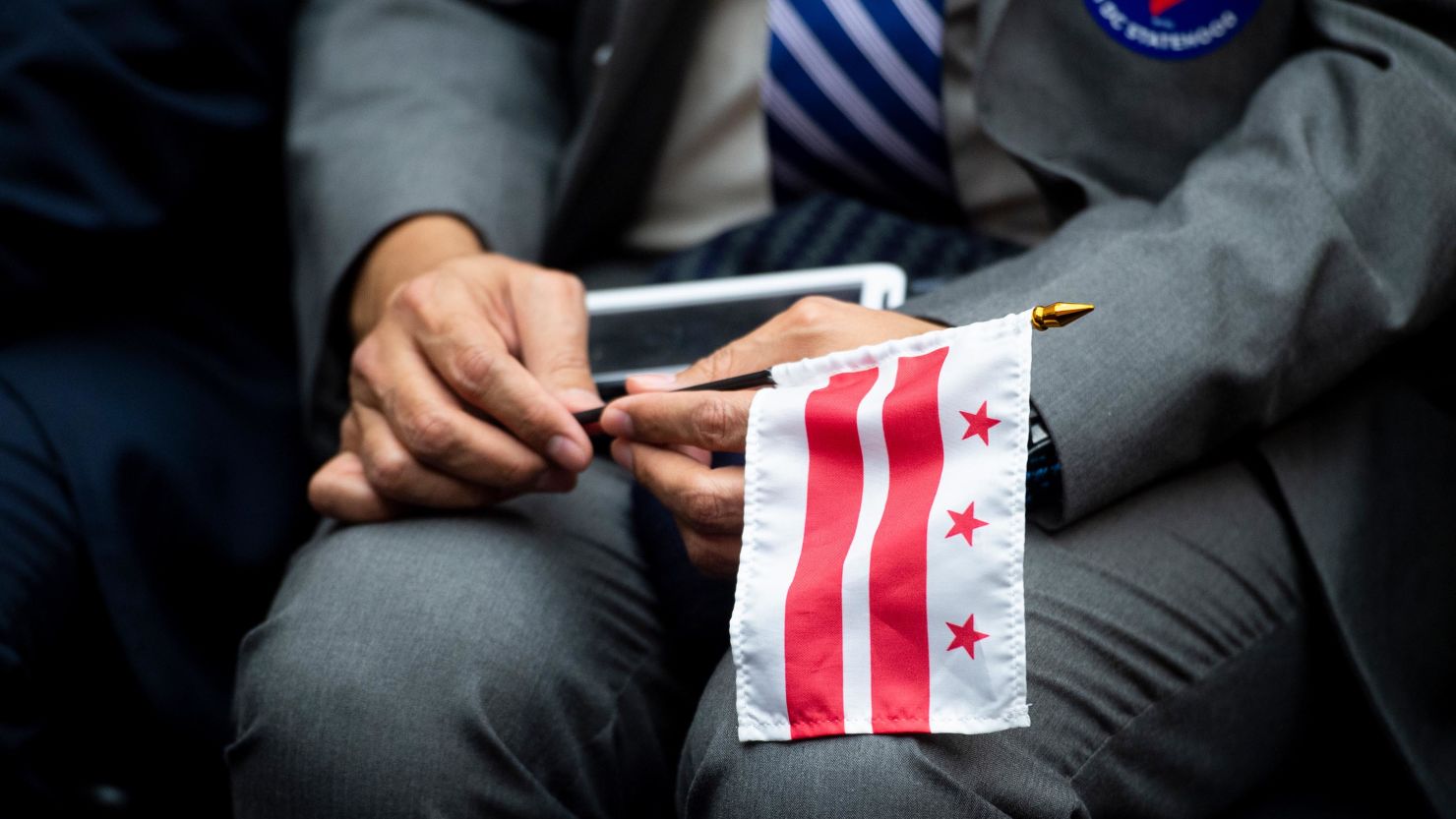In this Feb. 11, 2020, file photo, a man holds a Washington, DC, flag during a House Oversight and Reform Committee hearing on DC statehood. 
