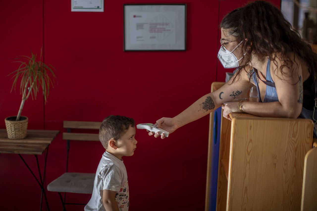 Hugo, 3, has his temperature taken by a teacher as he arrives at kindergarten in Barcelona on June 26.