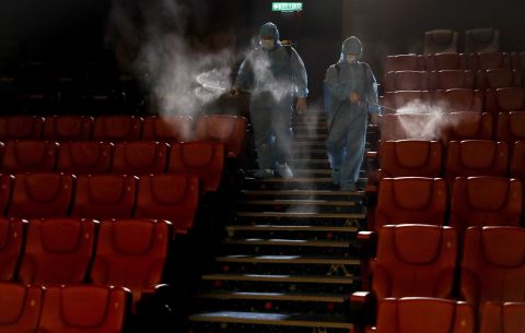 Staff members spray disinfectant inside a movie theater in Kuala Lumpur, Malaysia, on June 26. The theater was preparing for its reopening on July 1.