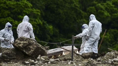 Men wearing protective equipment bury a coronavirus victim at a cemetery 14 km north of Honduras' capital, Tegucigalpa, on June 21, 2020.
