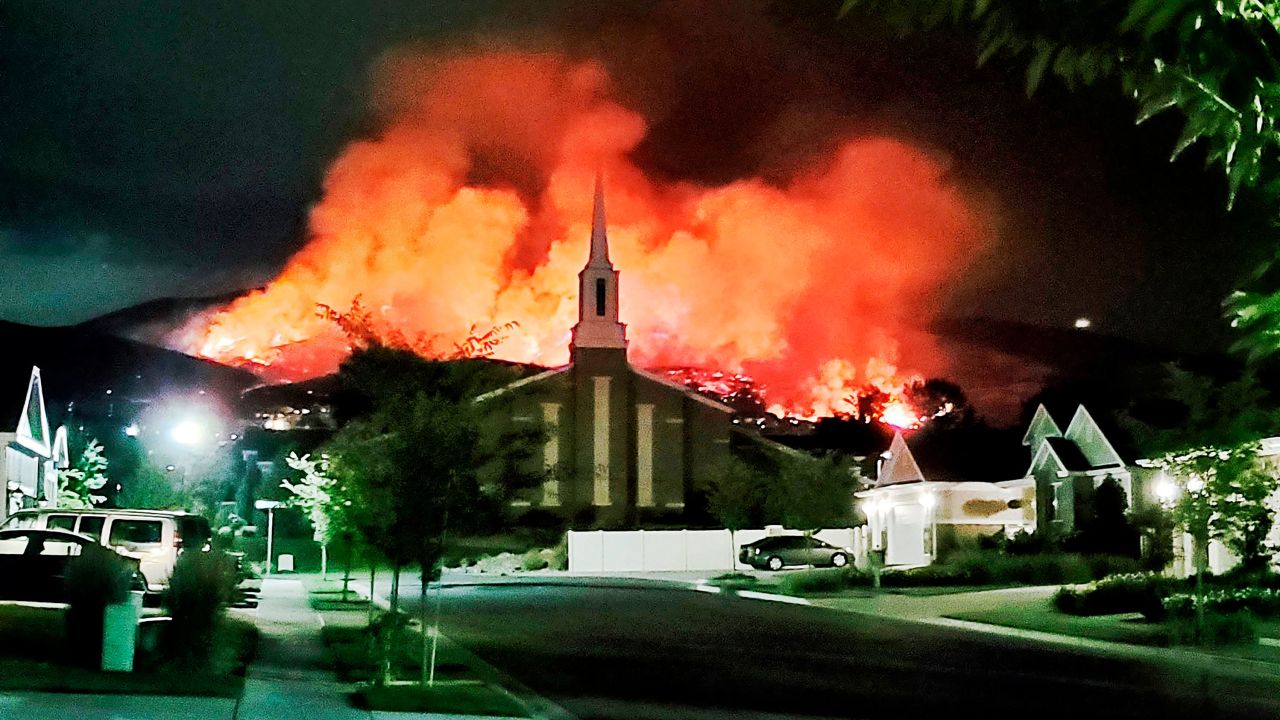 The Traverse Fire burns behind homes in Lehi, Utah, on Sunday. Officials say fireworks caused the wildfire and forced evacuations early Sunday morning.