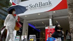 People walk past a SoftBank telecommunications store along a street in Tokyo on June 23, 2020. - Japanese tech investment behemoth SoftBank Group said on June 23, 2020 it will sell T-Mobile shares worth over 21 billion USD as it sheds assets to shore up its financial health.
