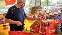 A shopper wearing a face mask on Monday, July 29, browses for fireworks at Wild Willy's Fireworks tent in Omaha, Neb., ahead of the Fourth of July holiday. Consumer fireworks sales have soared amid the coronavirus pandemic.