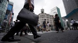 People walk across a pedestrian crossing at Ginza shopping district in Tokyo Wednesday, June 24, 2020.