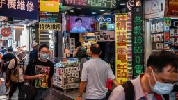 Pedestrians wearing protective masks walk past an electronics store showing Hong Kong Chief Executive Carrie Lam on a television screen in Hong Kong, China, on Tuesday, June 30, 2020.