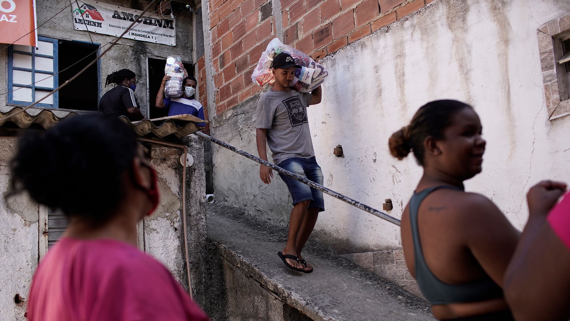 Residents carry food donated by a non-governmental agency amid the new coronavirus pandemic, in the Mandela slum, in Rio de Janeiro, Brazil, on  April 21