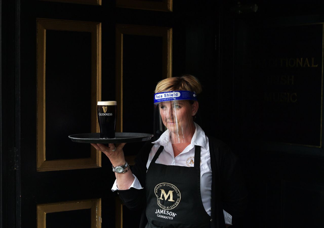 A member of the bar staff at Murray's Pub serves a pint of Guinness in Dublin, Ireland, on June 29. People in Ireland are tentatively returning to shops, hair salons and restaurants <a href="index.php?page=&url=https%3A%2F%2Fwww.cnn.com%2Ftravel%2Farticle%2Fireland-reopens-blarney-stone-scli-intl%2Findex.html" target="_blank">as the country emerges from its coronavirus lockdown.</a>