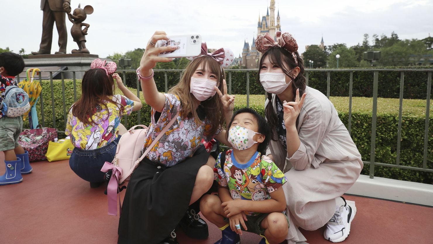 Visitors pose for photo during the reopening of Tokyo Disneyland on July 1, 2020. Disneyland reopened on the same day for the first time in about four months due to an outspread of coronavirus COVID-19. ( The Yomiuri Shimbun via AP Images )