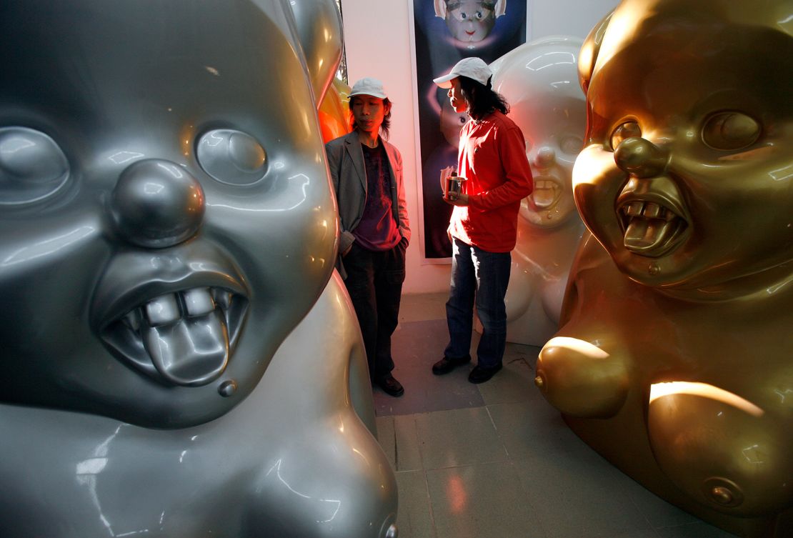 Chinese artists the Gao Brothers walk past some of their "Miss Mao" pieces in their Beijing studio in October 16, 2007.