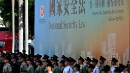 Attendees from various forces stand next to a banner supporting the new national security law during a flag-raising ceremony to mark China's National Day celebrations early morning in Hong Kong on July 1, 2020. - Hong Kong marks the 23rd anniversary of its handover to China on July 1 under the glare of a new national security law imposed by Beijing, with protests banned and the city's cherished freedoms looking increasingly fragile. (Photo by Anthony WALLACE / AFP) (Photo by ANTHONY WALLACE/AFP via Getty Images)